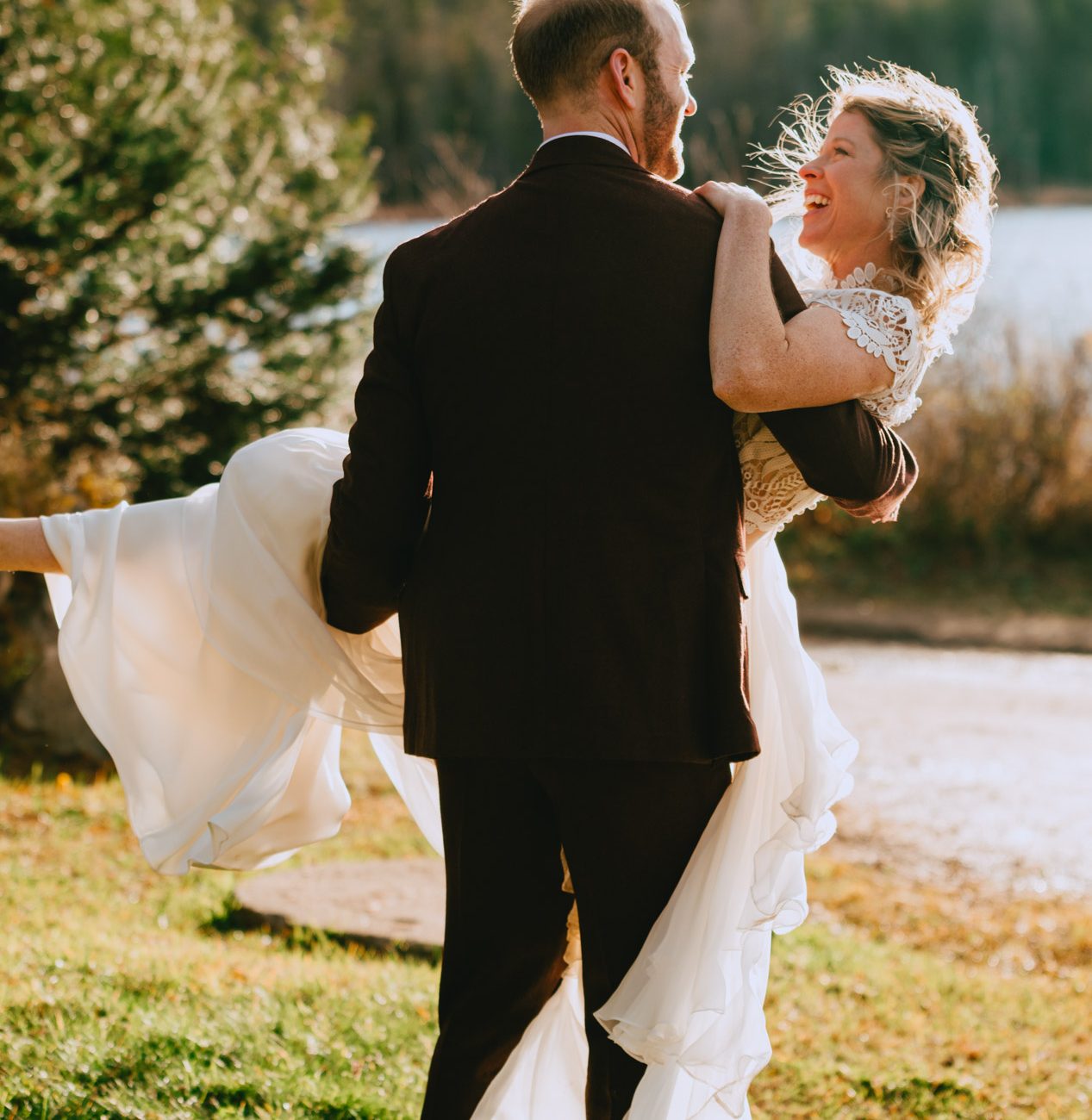 Séance photo des mariés. Le marié soulève sa mariée en princesse.